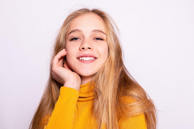 Trendy belle fille hipster Photo de positive jeune femme agréable en genou jaune avec fond blanc regardant la caméra et souriant