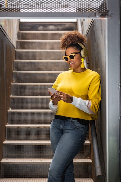 Trendy hipster femme noire dans les écouteurs navigation smartphone