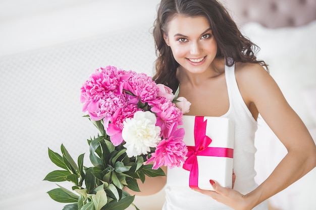 Très belle femme avec des fleurs et des cadeaux à l'intérieur