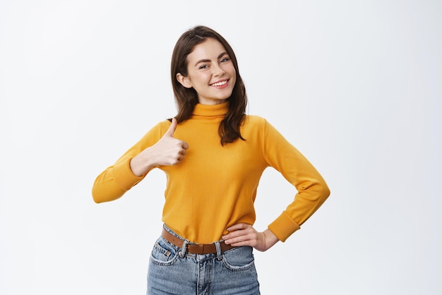 Très bon travail agréable Fille confiante souriante avec un maquillage de lumière naturelle montrant le pouce vers le haut en signe d'approbation Une femme aime et est d'accord avec vous montrant un soutien de choix fond blanc