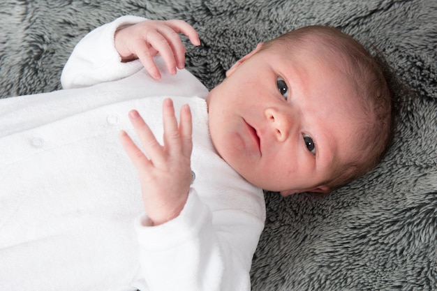 Très mignon bébé d'un mois dans une couverture grise