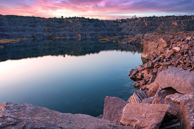 Un très petit lac magnifique entouré de gros tas de déchets de pierre du travail acharné dans la mine