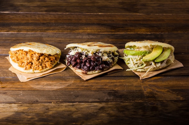 Tres tipos de arepas, comida latinoamericana en una mesa de madera