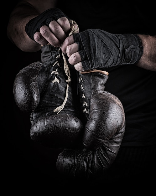 Très vieux gants de sport de boxe dans les mains des hommes