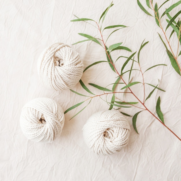 Tressage en macramé fait main et fils de coton avec branche de feuilles vertes. Image claire bonne pour les bannières et la publicité en macramé et artisanat. Passe-temps féminin. Vue de dessus