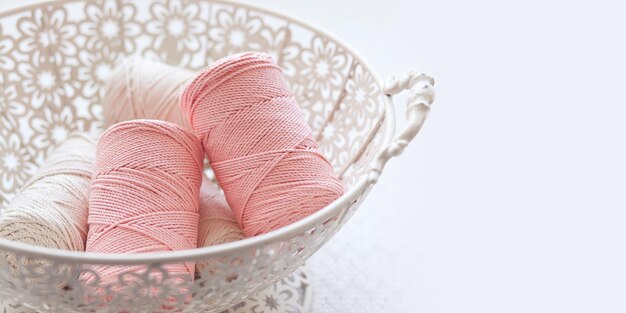 Tressage en macramé fait main et fils de coton dans un panier sur fond blanc Cordons en macramé de coton