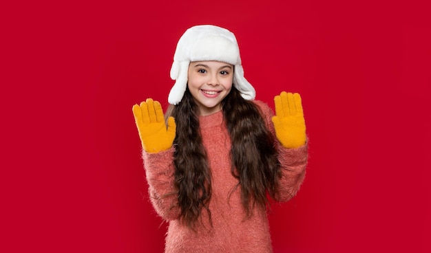 Tricots d'hiver adolescente modèle en chapeau à oreillette mains en l'air adolescente en chapeau d'hiver isolé sur rouge