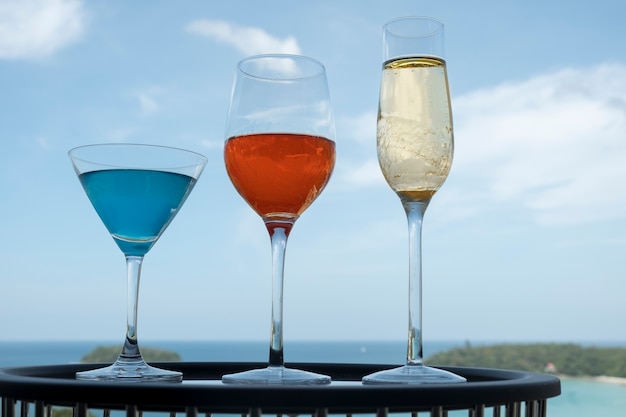 Triple de verre à cocktail sur la belle table et un fond de ciel brillant-miroir