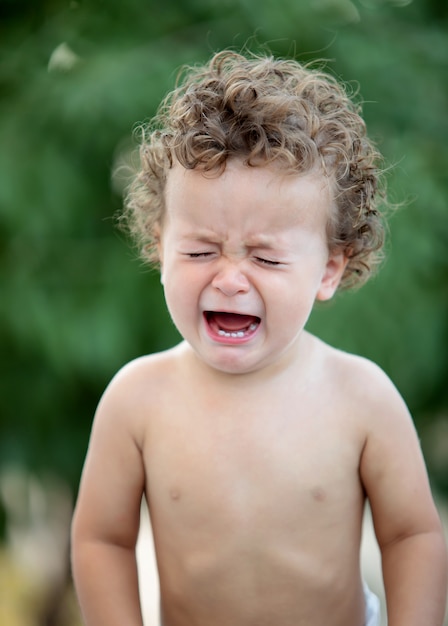 Triste bébé aux cheveux bouclés qui pleure