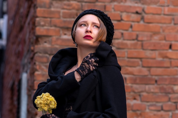 Triste belle femme dans un style rétro sur un fond de mur de briques