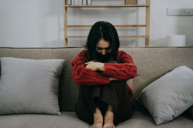 Triste et déprimée jeune femme assise sur le canapé humeur triste se sentir fatiguée concept solitaire et malheureux