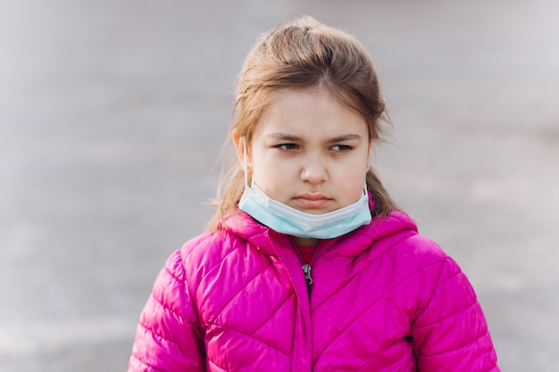 Triste, déprimée petite fille en protection médicale stérile contre le masque de virus à l'extérieur. Soins de santé, épidémie, pandémie, concept de maladie