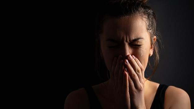 Triste désespérée pleurer pleurer femme avec les mains jointes et les larmes aux yeux