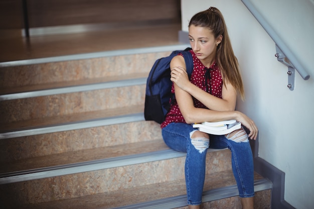 Triste écolière assise seule sur l'escalier