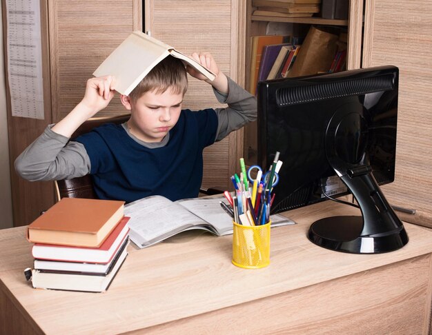 Triste et fatigué écolier pré-adolescent assis dans le stress travaillant à faire ses devoirs dans sa chambre