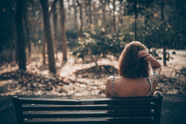 Triste femme assise sur le banc dans le style vintage du parc