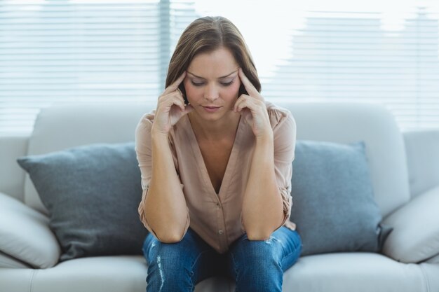 Triste femme assise sur un canapé