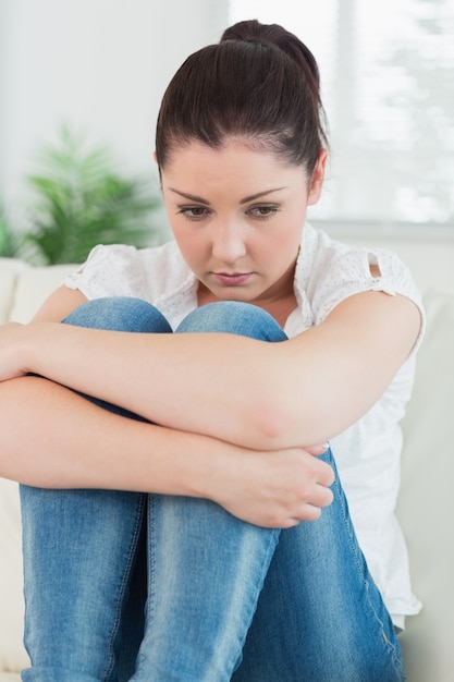 Triste femme assise dans le salon sur un canapé