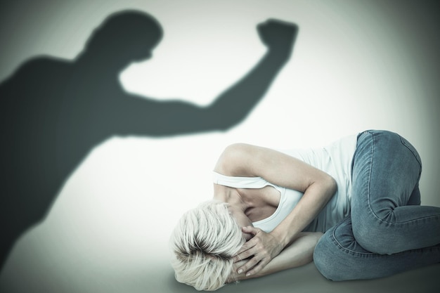 Photo triste femme blonde allongée sur le sol contre la silhouette d'un sportif acclamant