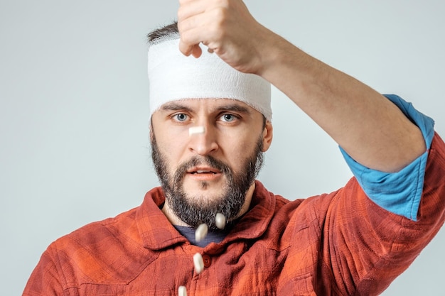 Triste homme bandé blessé avec des pilules sur fond gris