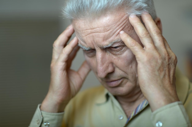 Triste homme senior malade avec mal de tête