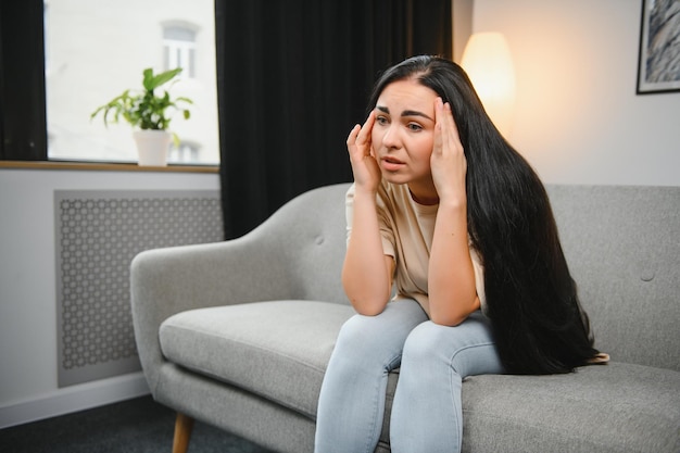 Triste jeune femme fatiguée touchant le front ayant des maux de tête migraine ou dépression bouleversée fille frustrée troublée par le problème se sentir stressée couvrir pleurer le visage avec la main souffrir du concept de chagrin chagrin