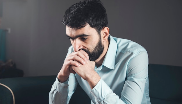 Triste malheureux bel homme assis sur le canapé