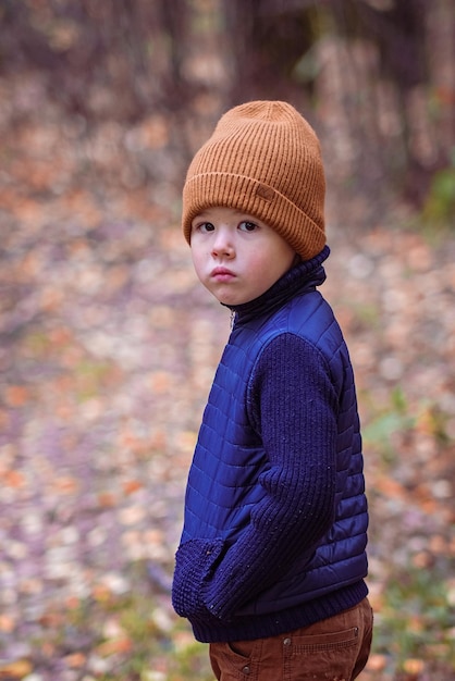 Triste petit garçon dans le parc d'automne marchant