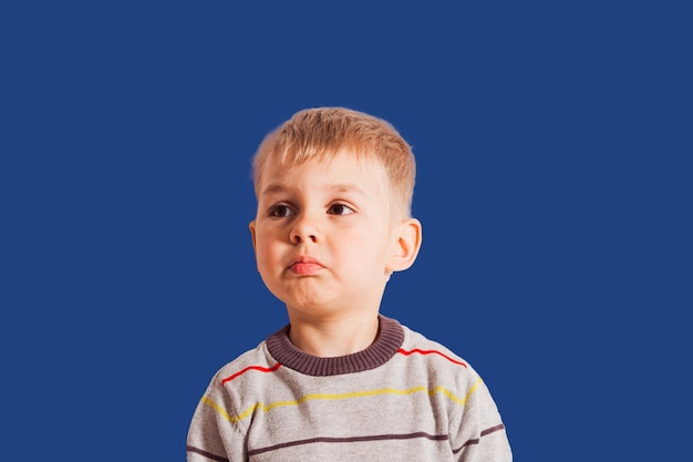 Triste petit garçon sur fond bleu Portrait d'enfant avec espace de copie