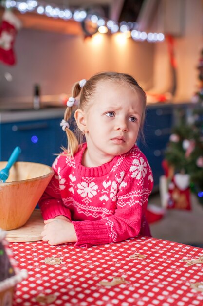 Triste petite fille préparant des biscuits de pain d'épice de Noël