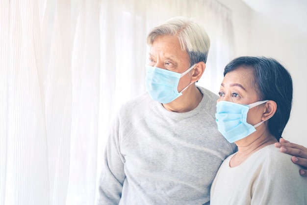 Triste vieux couple se tient près de la fenêtre pendant la quarantaine