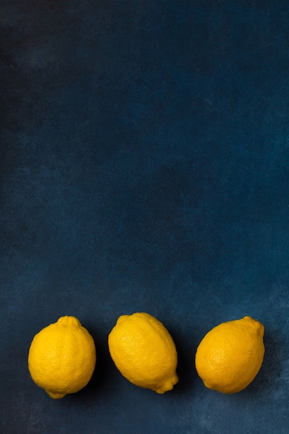 Trois agrumes jaune vif sur une vue de dessus de fond bleu