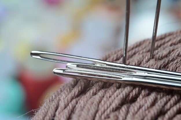 Photo trois aiguilles à coudre sont insérées dans une bobine de fil. fermer.