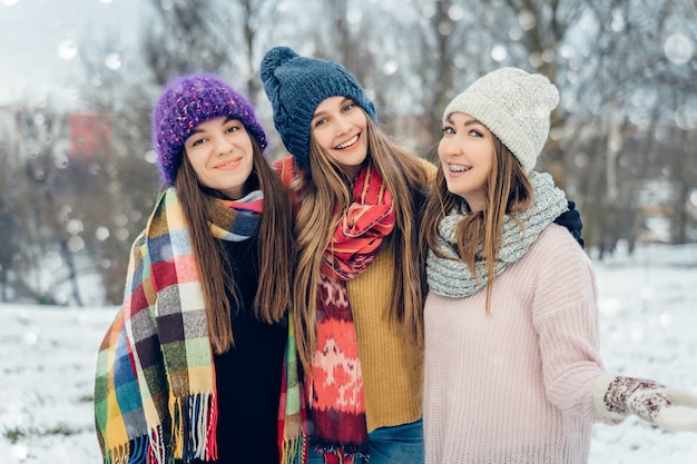 Trois amies à l'extérieur dans des chapeaux tricotés s'amusant par temps froid et neigeux