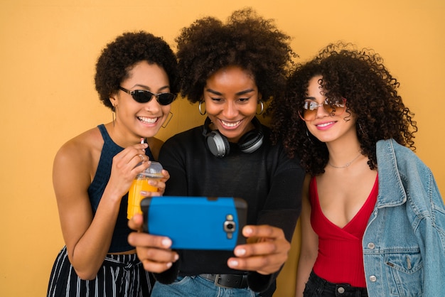 Trois amis afro prenant des selfies avec téléphone.