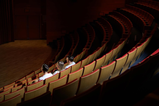 Trois amis dans la salle de cinéma, une fille et deux garçons s'amusant à regarder un film dans le film vide