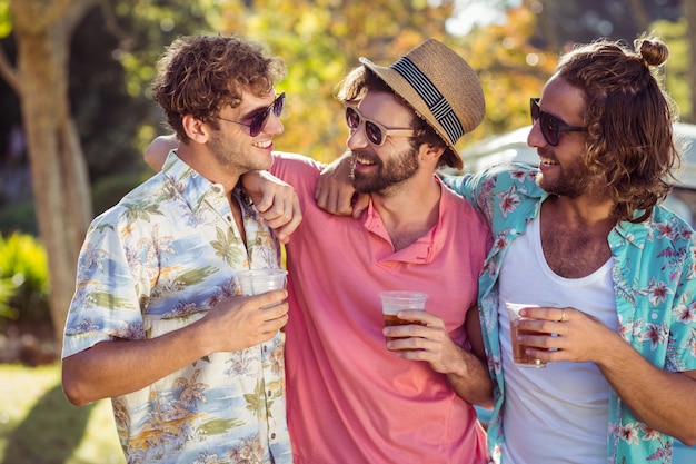 Trois amis heureux debout avec des verres de bière