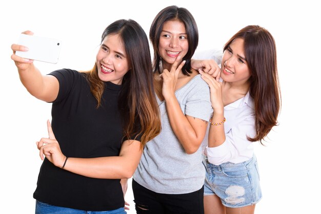 Trois amis heureux jeune femme asiatique souriant tout en prenant une photo de selfie avec un téléphone mobile