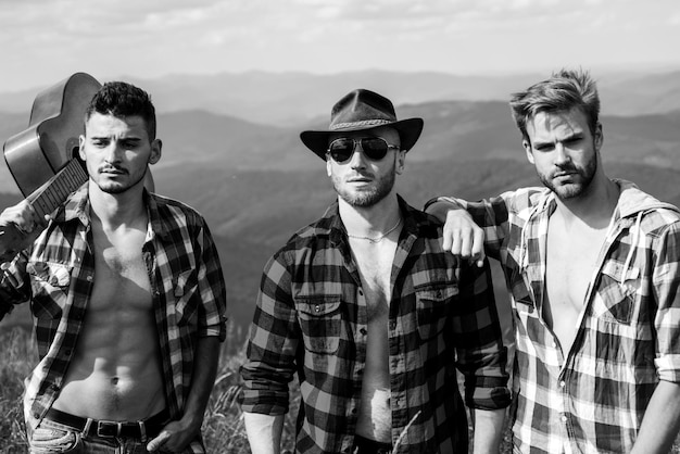 Trois amis heureux regardent les montagnes et s'amusent ensemble des jeunes faisant de la randonnée dans la nature y