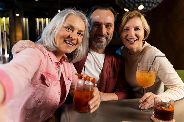 Photo trois amis plus âgés prenant un selfie dans un restaurant