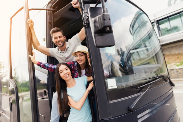 Trois amis de touristes sortent des portes du bus.