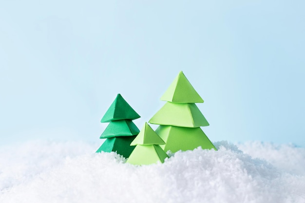 Trois arbres de Noël en papier vert sur une neige.