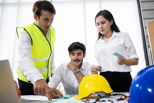 Trois architectes au bureau et discutant du projet de conception.