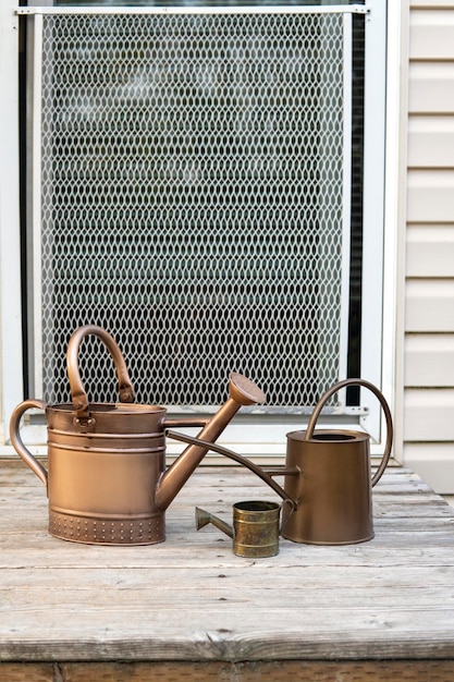Trois arrosoirs en métal de différentes tailles sur le porche en bois. Famille d'arrosoirs