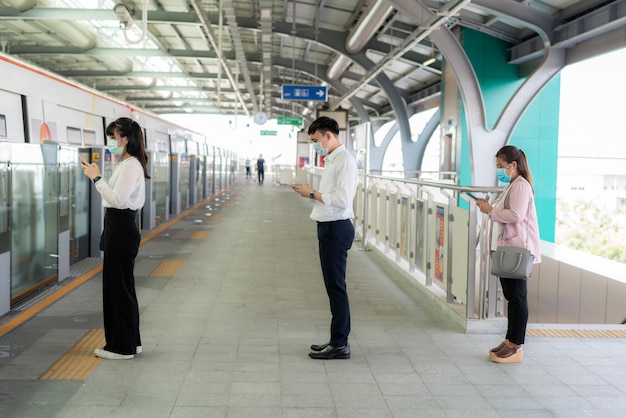 Trois Asiatiques portant un masque à une distance de 1 mètre des autres personnes gardent une distance à l'abri des virus COVID-19 et de l'éloignement social