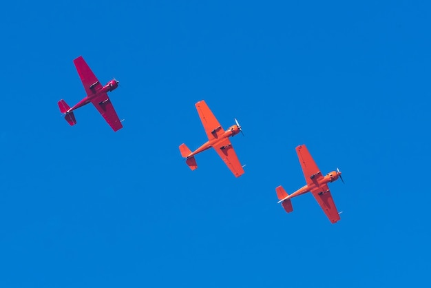 Trois avions rouges à turbopropulseurs légers volent en formation en ligne droite dans le ciel