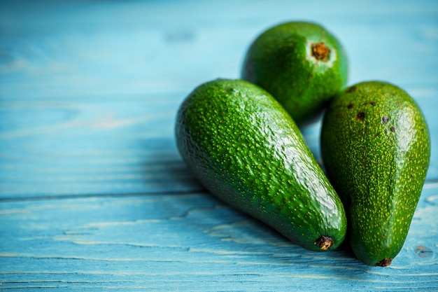 Trois avocats verts sur mur en bois