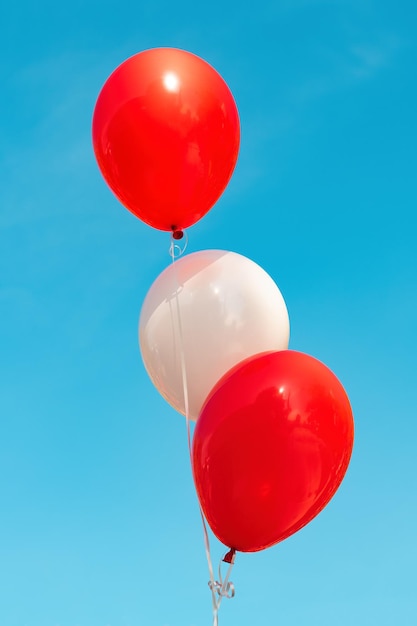 Trois ballons, rouge et blanc contre le ciel bleu