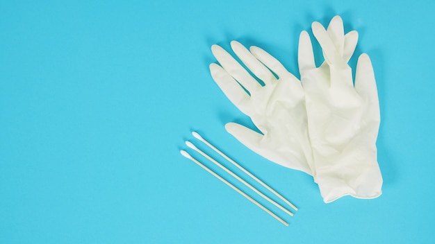 Trois bâtons de coton avec des gants médicaux blancs ou un gant en latex sur fond bleu.concept covid-19, pas de personnes