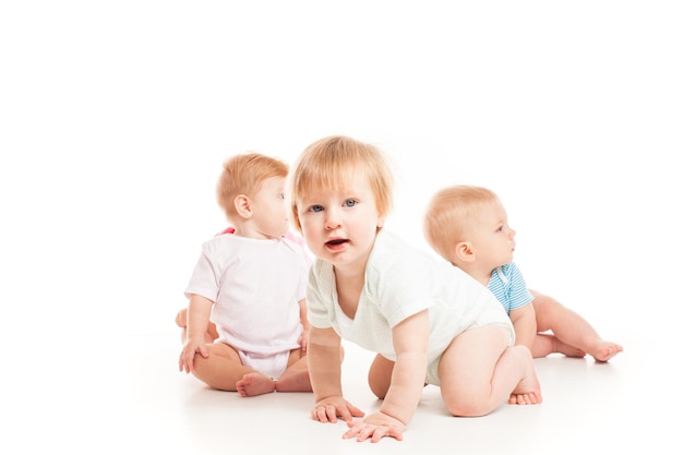 Trois bébés assis isolés sur le blanc